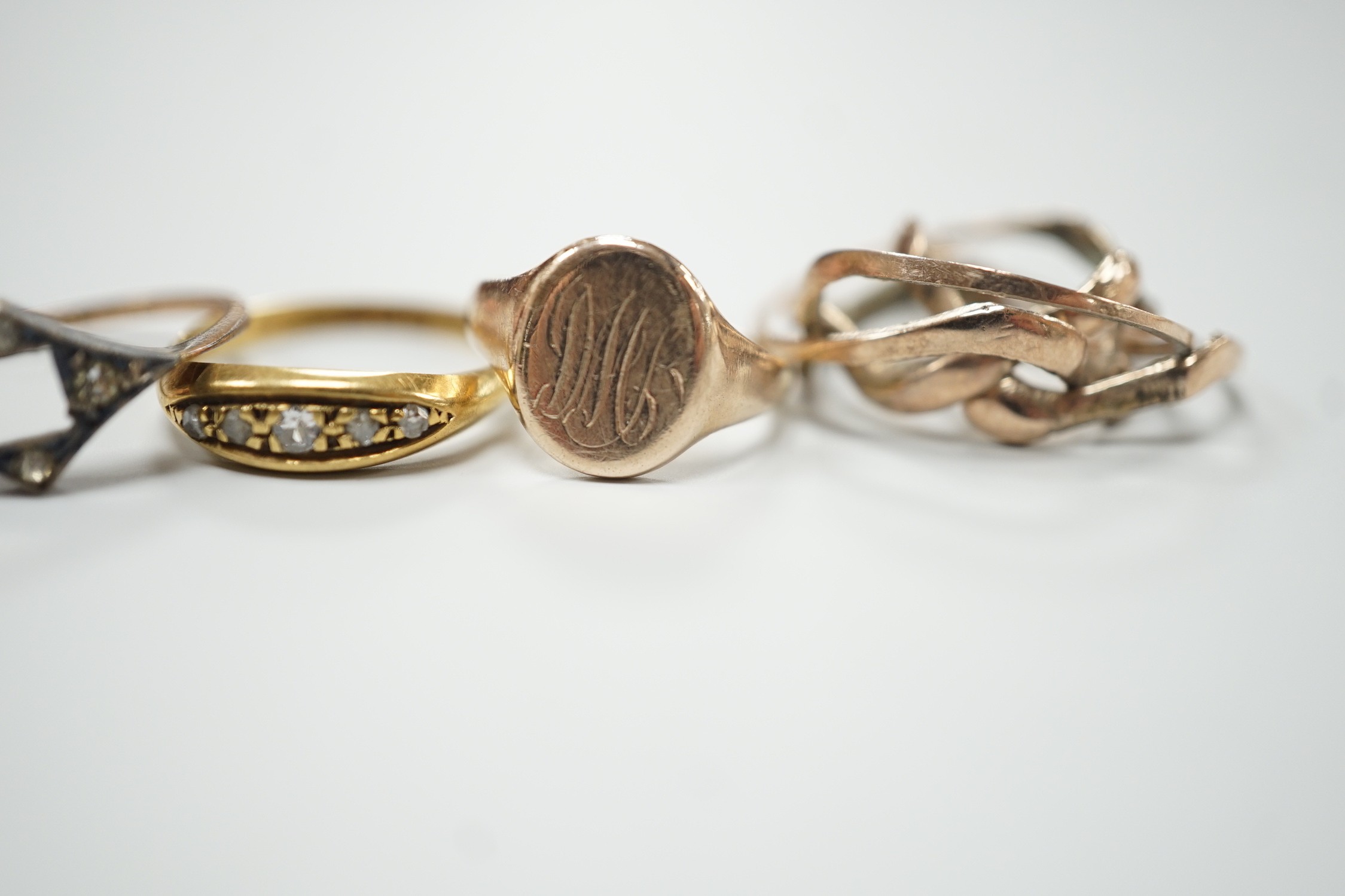 An 18ct gold and five stone diamond chip set ring, size L, gross 2.7 grams, two 9ct rings including small signet, gross 3.4 grams and a yellow metal puzzle ring.